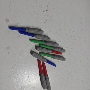 Pu&ograve; includere: Una collezione di spade laser giocattolo in vari colori, tra cui blu, verde e rosso. Le spade laser hanno impugnature grigie e sono disposte su una superficie chiara.