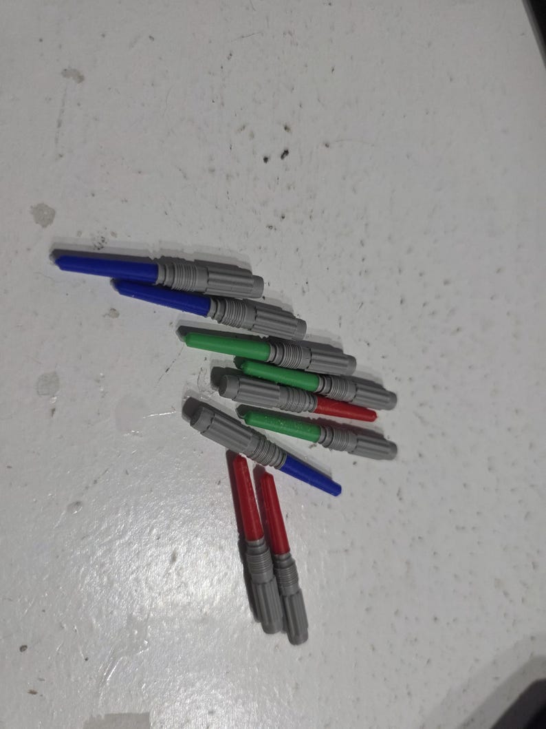 Pu&ograve; includere: Una collezione di spade laser giocattolo in vari colori, tra cui blu, verde e rosso. Le spade laser hanno impugnature grigie e sono disposte su una superficie chiara.