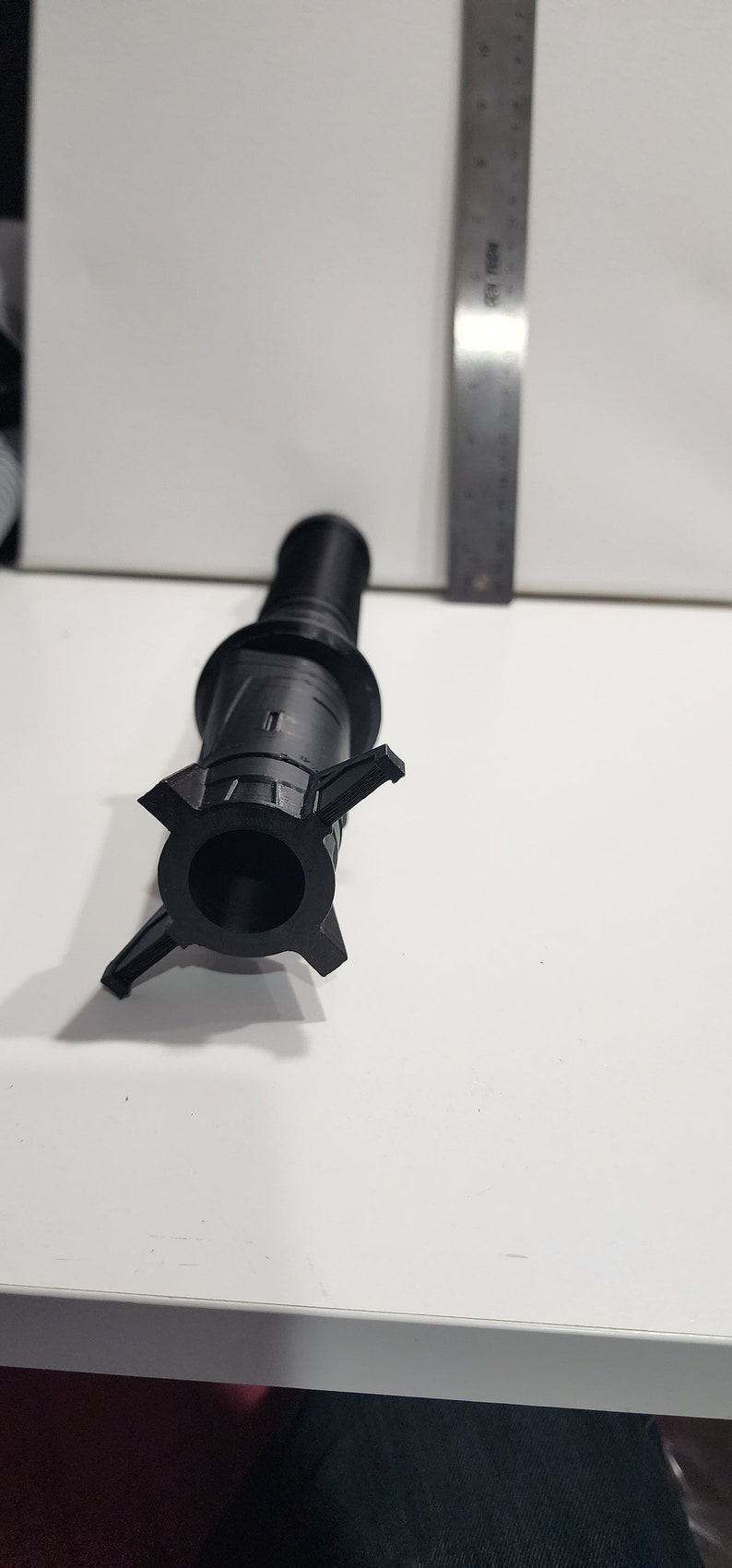 May include: A black plastic 3D printed object with a cylindrical body and a five-pointed star-shaped base.