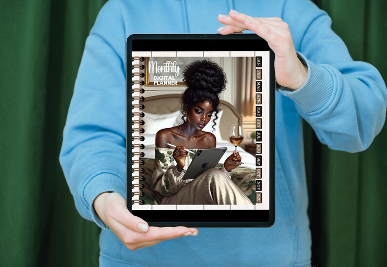 May include: A digital planner with a black and white cover featuring a woman with dark skin and long black hair. The cover text reads "Monthly Digital Planner". The planner has a spiral binding and a side bar with the months of the year.