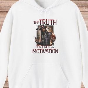 Puede incluir: Sudadera con capucha blanca con un estampado gráfico de un hombre con sombrero y gafas de sol que sostiene un micrófono y un vaso de líquido. El texto "THE TRUTH DON'T NEED NO MOTIVATION" está impreso en la sudadera.