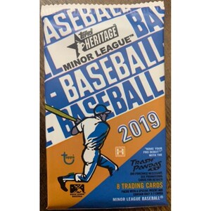 Puede incluir: Un paquete de cartas de intercambio de béisbol de la Liga Menor Topps Heritage con un jugador de béisbol con un uniforme azul y blanco balanceando un bate. El paquete es naranja y azul con el texto "Topps Heritage Minor League Baseball 2019" y "Trash Pandas".