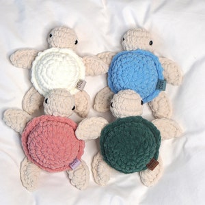May include: Four crocheted turtle toys with different colored shells. The turtles are white with beige accents and have brown "Handmade with Love" tags.