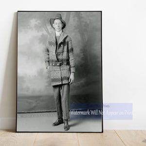 May include: A black and white photograph of a person wearing a patterned coat and a hat. The person is standing in front of a blurred background.