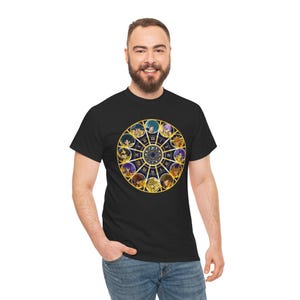 Könnte beinhalten: Schwarzes T-Shirt mit einem goldenen Tierkreisrad-Design. Das Rad zeigt Charakterillustrationen, römische Ziffern und ein zentrales kreisförmiges Muster. Das T-Shirt ist aus weichem Material.