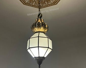 May include: An ornate, hanging Moroccan-style lamp with a geometric design. The lamp has a white, geometric shade and is suspended from a decorative ceiling fixture. The text "Morocco art by Ahmed" is visible.