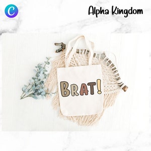 May include: A white tote bag with the word "BRAT!" printed in colorful, outlined letters. The letters are in shades of brown, pink, and yellow.