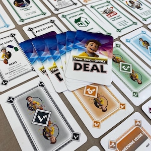 Może przedstawiać: Zbiór kart do gry Monopoly Deal. Karty mają różne wzory, w tym karty akcji, karty własności i karty transakcji. Schemat kolorów obejmuje biały, zielony, niebieski, pomarańczowy i brązowy. Tekst na kartach zawiera "Action Card", "Rent" i "Deal".