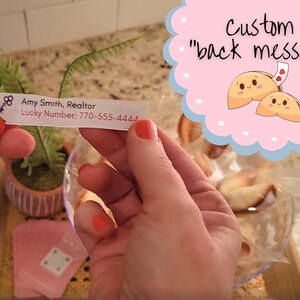 woman holding the custom fortune message showing the back of the message with the bowl of fortune cookies in the background