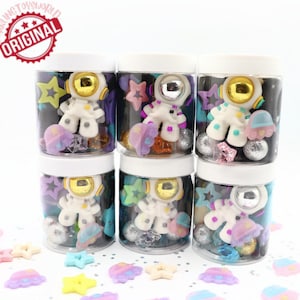 May include: Six clear plastic jars with white lids filled with colorful slime and astronaut-themed charms. The charms include astronauts, stars, and spaceships. The jars are arranged in two rows of three.