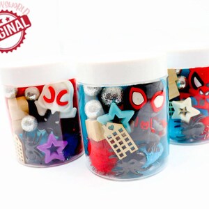 May include: Three clear plastic jars filled with various colorful items, including red, blue, and silver glitter, black spiders, stars, and a red Spiderman figure. The jars have white lids and are labeled with the letters "JC".