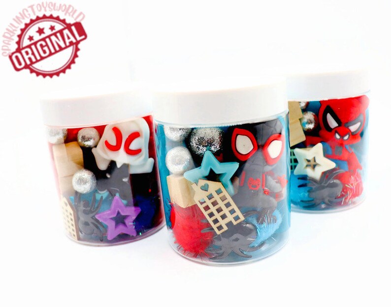 May include: Three clear plastic jars filled with various colorful items, including red, blue, and silver glitter, black spiders, stars, and a red Spiderman figure. The jars have white lids and are labeled with the letters "JC".