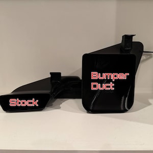 K&ouml;nnte beinhalten: Schwarze Autoteile mit den roten Aufschriften "Stock" und "Bumper Duct". Die Teile bestehen aus gl&auml;nzendem schwarzem Material und werden auf einer wei&szlig;en Oberfl&auml;che pr&auml;sentiert.