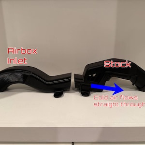 K&ouml;nnte beinhalten: Zwei schwarze Kfz-Luftansaugkomponenten werden gezeigt. Das linke Teil ist mit "Airbox Inlet" beschriftet, das rechte Teil mit "Stock". Ein blauer Pfeil zeigt den Luftstrom an, mit dem Text "Cold air flows straight through."