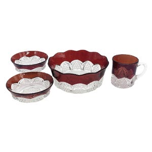 Peut inclure: Ensemble de quatre bols en verre transparent avec un bord rouge et un motif de verre taillé complexe. L'ensemble comprend un grand bol, deux petits bols et une tasse.