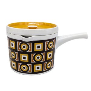 Peut inclure: Une casserole en céramique blanche et marron avec un couvercle jaune. La casserole présente un motif géométrique de carrés et de cercles en marron, jaune et blanc. Elle est dotée d'une longue poignée blanche.