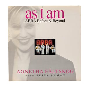 May include: A square book cover titled As I Am ABBA Before & Beyond by Agnetha Fältskog with Brita Åhman. The cover features a faded, monochromatic portrait of a person and a central rectangular inset showing the four members of the band ABBA.