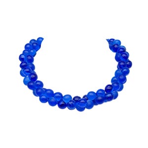 Peut inclure: Un collier composé de perles de verre bleues. Les perles sont rondes et ont une finition givrée. Le collier est disposé en cercle.