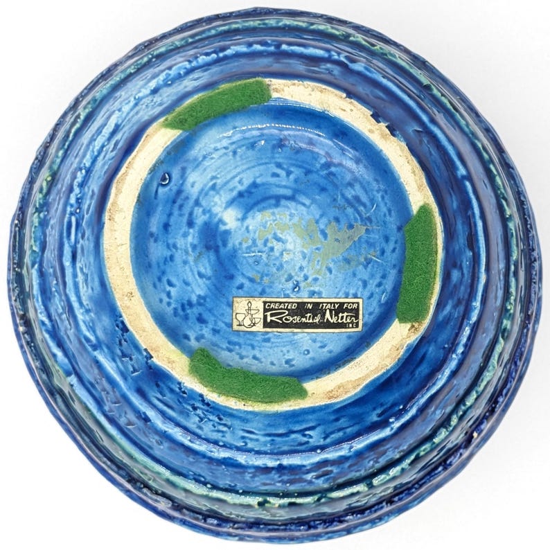 Op de afbeelding: Blauwe en groene keramische kom met een getextureerd oppervlak. De onderkant van de kom heeft een label met de tekst "Created in Italy for Rosenthal Netter Inc."