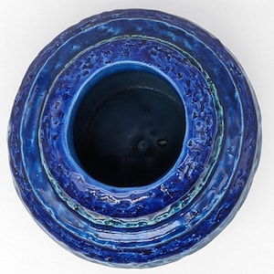 Op de afbeelding: Een blauwe keramische vaas met een getextureerd, gelaagd ontwerp. De vaas heeft een brede opening en een ronde vorm.