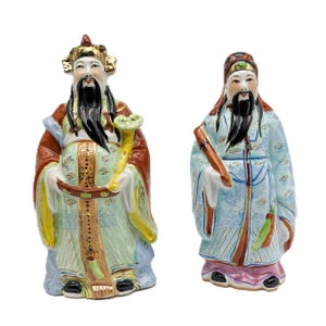 Peut inclure: Deux figurines en porcelaine de dieux chinois, l'une en robe bleue et dorée tenant un rouleau, l'autre en robe verte et dorée tenant un bâton.