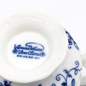 Pu&ograve; includere: Primo piano del fondo di una tazza da t&egrave; bianca con un motivo floreale blu. L'iscrizione "Vienna Woods Fine China" &egrave; stampata in blu sul fondo della tazza.