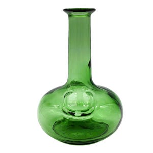 Puede incluir: Una botella de vidrio verde con una base redondeada y un cuello largo y cilíndrico. La botella tiene una pequeña hendidura circular en la parte delantera. El vidrio tiene una ligera textura y un acabado brillante. La botella está vacía y se encuentra sobre un fondo blanco.