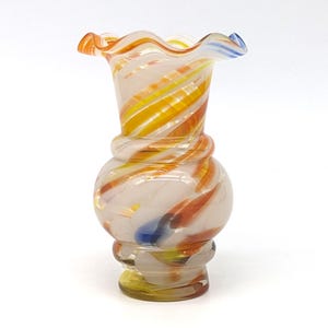 Peut inclure: Un vase décoratif en verre avec un bord froncé. Le vase présente un corps bulbeux et un motif tourbillonnant de couleurs orange, jaune, blanc et bleu. Le vase est un objet décoratif.