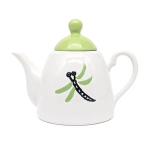Può includere: Teiera in ceramica bianca con coperchio verde e un design di libellula. La libellula è dipinta in nero e verde.