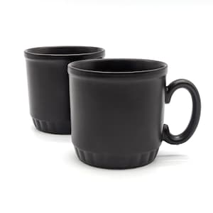 Può includere: Due tazze in ceramica nera con finitura opaca. Una tazza ha un manico ed entrambe hanno una base leggermente strutturata. Le tazze sono cilindriche con un design semplice e moderno, per caffè o tè.