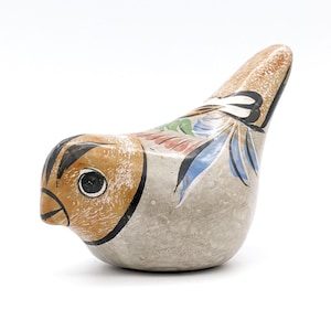 Puede incluir: Una figurita de pájaro de cerámica pintada a mano con detalles en marrón, blanco, azul y verde. El pájaro tiene una cara detallada y un diseño caprichoso.