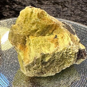 May include: A large, rough, yellow-green rock with a textured surface. The rock has a natural, organic shape and appears to be a type of mineral or gemstone.