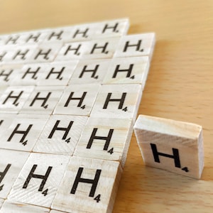May include: A close-up of a group of wooden letter tiles, each with the letter 'H' and the number '4' printed on them. The tiles are arranged in a staggered pattern, with the top row slightly offset from the bottom row. The tiles are all white and have a smooth, polished finish.