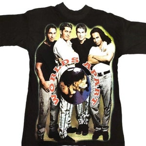 May include: Black t-shirt featuring a graphic of a boy band with the text "Worlds Apart" in a circular design. The band members are depicted in various poses, wearing casual attire. The shirt is a vintage style.