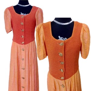 Pode incluir: Um vestido laranja com corpete de malha e detalhes de botões. O vestido apresenta mangas curtas bufantes e uma saia fluida. O corpete é de um tom de laranja mais escuro que a saia, criando um contraste. O vestido é exibido em um manequim preto.
