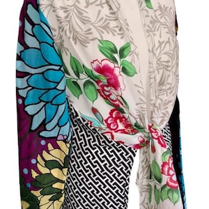 Könnte beinhalten: Ein gemustertes Wickeloberteil auf einer Schaufensterpuppe. Der Wickel hat florale, geometrische und abstrakte Designs in Blau, Lila, Grün, Rosa und Schwarz. Das Oberteil ist in der Taille gebunden.