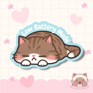 May include: A sticker depicting a cartoon cat in a resting pose, with the text "Low Battery Mode" in a blue bubble. The cat is brown and white with pink accents, and the sticker has a light blue border.