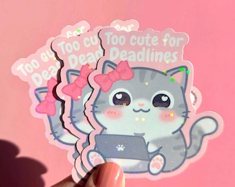 Könnte beinhalten: Mehrere holografische Aufkleber mit einer Cartoon-Katze mit einer rosa Schleife, die einen Laptop hält. Die Katze ist grau und weiß mit Sternakzenten. Der Text auf dem Aufkleber lautet "Too cute for Deadlines" auf rosa Hintergrund.