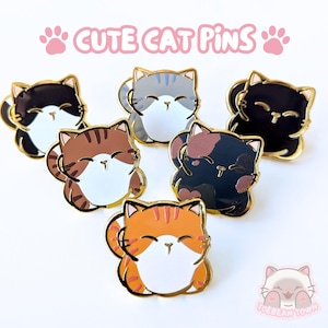 Pode incluir: Uma coleção de seis pins de esmalte com desenhos de gatos de desenho animado em várias cores, incluindo preto, cinza, marrom e laranja, com contornos dourados. Os pins têm uma expressão sorridente. O texto "CUTE CAT PINS" é exibido acima.