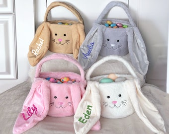 May include: Four plush bunny-shaped Easter baskets with embroidered names: Rachel, Amelia, Lily, and Eden. Each basket is filled with colorful plastic Easter eggs.