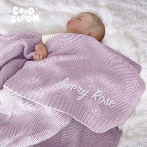May include: A soft, lavender knitted baby blanket with the name "Avery Rose" embroidered in white.