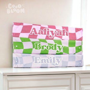 Peut inclure: Trois bacs de rangement empilables avec des motifs &agrave; carreaux en rose, vert et bleu. Chaque bac porte un nom : Aaliyah, Brody et Emily.