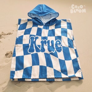 May include: Blue and white checkered hooded towel with the name "Krue" in a retro font.