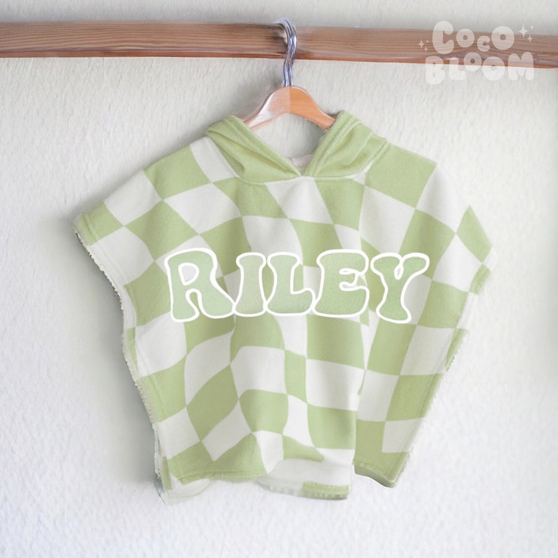 Peut inclure: Un poncho &agrave; capuche &agrave; carreaux verts et blancs avec le nom "RILEY" dans une police r&eacute;tro.