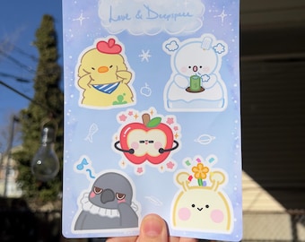 May include: A sheet of stickers featuring cute cartoon characters. The stickers are on a blue background with white clouds and stars. The characters include a chicken, a snowman, an apple, a bird, and a creature with a flower on its head. The text "Love & Deep Space" is written at the top of the sheet.