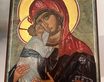 Könnte beinhalten: Religiöse Ikone, die eine Mutter und ein Kind zeigt, mit einem goldenen Heiligenschein und aufwendigen Details. Das Kunstwerk verwendet eine Farbpalette aus Rot, Schwarz und Gold, mit Text oben und unten. Das Bild ist mit einem grünen Rahmen versehen.