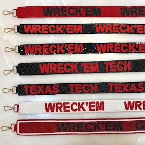 May include: A collection of beaded straps in various colors, including red, black, and white. The straps feature the text "WRECK'EM" and "TEXAS TECH" in bold red lettering. Each strap has a metal clasp.