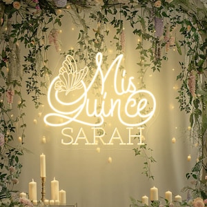 Może przedstawiać: Biały neonowy znak z tekstem "Mis Quince" i wzorem motyla. Znak zawiera również imię "SARAH" pod tekstem. Znak wisi przed kwiatowym łukiem z białymi świecami po obu stronach.