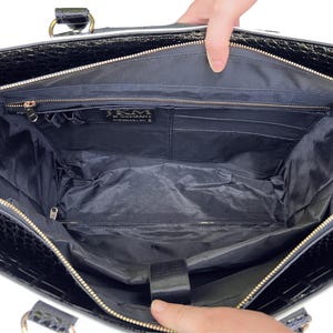 Interior of the white and black wheeled work tote purse shown empty, revealing padded laptop compartment, pen slots, and multiple organizer pockets including a large pocket with zipper. Perfect for women looking for a rolling bag for business, nursing school, or travel. This wheeled laptop tote fits 15.6" laptops and is ideal for organizing work supplies. Use as a flight-ready women’s rolling bag or travel weekender or thoughtful gift idea for teachers or business travelers with a lot to carry.