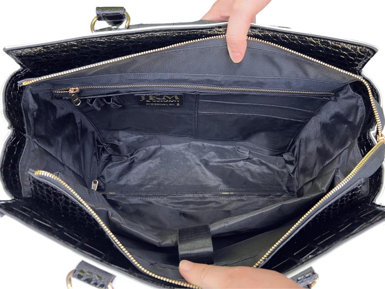 Interior of the white and black wheeled work tote purse shown empty, revealing padded laptop compartment, pen slots, and multiple organizer pockets including a large pocket with zipper. Perfect for women looking for a rolling bag for business, nursing school, or travel. This wheeled laptop tote fits 15.6" laptops and is ideal for organizing work supplies. Use as a flight-ready women’s rolling bag or travel weekender or thoughtful gift idea for teachers or business travelers with a lot to carry.